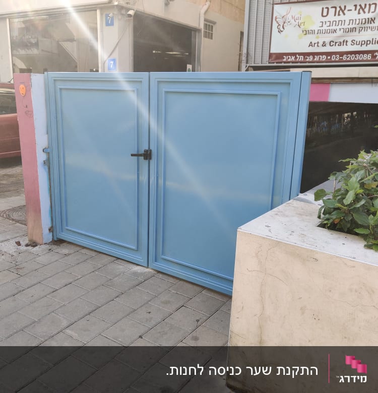 שער מתכת כחול עם ידית שחורה ברחוב